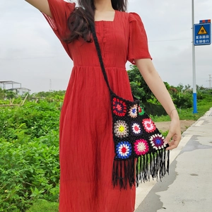 Detail of a vintage crochet crossbody bag with colorful floral patterns and long black tassels