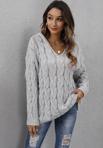 Detail of light grey cable knit texture on a loose V-neck hooded winter sweater
