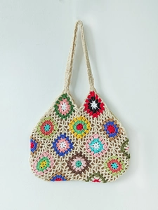 Detail of hand-crocheted tote bag with colorful granny square flower patterns and strap