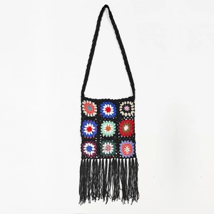 Detailed close-up of handmade crochet granny square bag with colorful patterns and black tassels