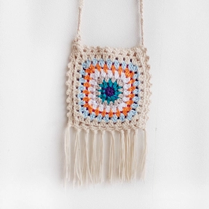 Detail of handmade crochet granny square bag featuring colorful patterns and long fringes
