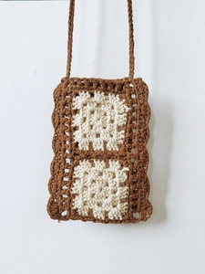 Detail of hand-woven crochet crossbody bag with contrast color grandmother square patterns