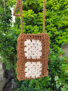 Detail of handcrafted crochet phone bag featuring contrast granny square patterns and knitting