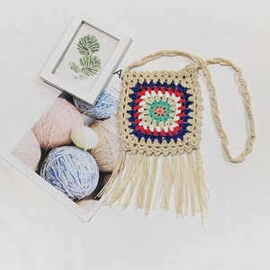 Macro detail of handmade crochet bohemian crossbody bag with colorful squares and fringe