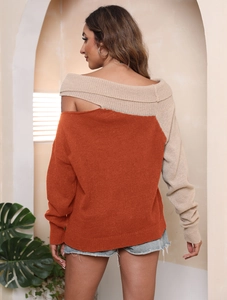 Dettaglio della maglia a contrasto arancione e beige con design a spalla scoperta