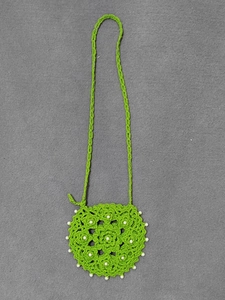 Detail of green handmade crochet crossbody bag with layered floral pattern and white pearls