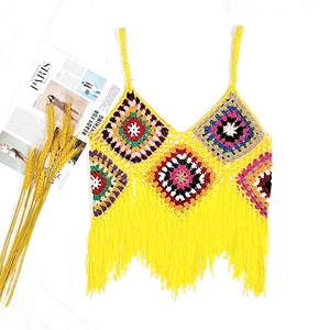Detail of colorful crochet geometric squares and long yellow tassels on a boho top