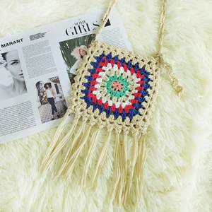 Close-up of handmade crochet crossbody bag with colorful flower pattern and long tassels