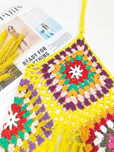 Detail of colorful granny square crochet halter top with boho fringe and woven textures