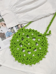 Detail of green crochet crossbody bag with floral patterns and pearl embellishments