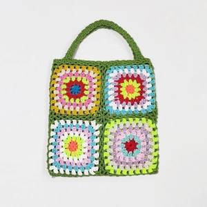Detailed view of colorful hand-crocheted granny square tote bag with dark green handles