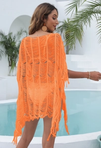 Detail of bright orange beach cover-up featuring long fringes and open knit texture