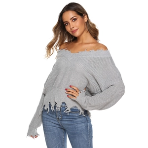 Close-up of light grey knit sweater showing distressed hem and fringe tassel details