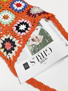 Detail of colorful granny square crochet handbag with bohemian orange flower patterns