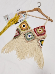 Detailed close-up of handmade crochet patchwork top with bohemian multi-color fringe hem