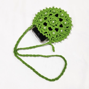 Detailed view of hand-crocheted green phone bag with floral patterns and pearls