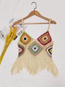 Detailed close-up of handmade crochet camisole featuring colorful floral patterns and long fringe