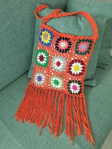 Detail shot of boho crochet shoulder bag with colorful granny squares and orange fringe
