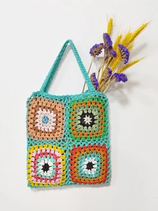 Detailed close-up of vibrant handmade granny square crochet tote bag with dried flowers
