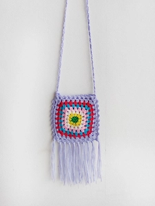 Close-up of handmade crochet bag with colorful granny squares and long tassel fringe