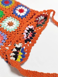 Close-up of colorful handmade crochet granny square patterns on a bohemian tassel bag