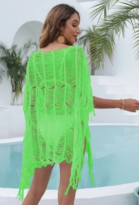 Detail of neon green beach cover-up featuring hollow crochet knit and fringe tassels