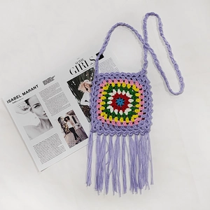 Detailed close-up of handmade crochet crossbody bag with purple fringe and ethnic pattern