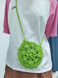 Detail of green crochet flower crossbody bag with pearl accents and adjustable strap
