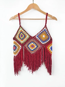Detailed close-up of handmade crochet granny square pattern with red fringe tassels