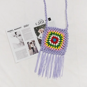 Detail of purple handmade crochet crossbody bag with vibrant granny square and long fringes