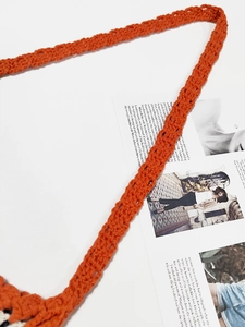Detail of hand-crocheted orange cotton shoulder strap with intricate hollow weave texture