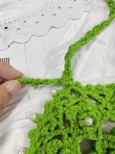Detail of green handmade crochet pattern with white faux pearl beads decoration
