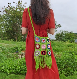 Outdoor shot of a colorful crochet crossbody bag with floral squares and green tassels
