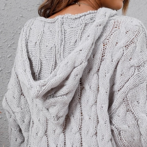 Detail view of the thick cable knit texture and large hood on a grey oversized sweater