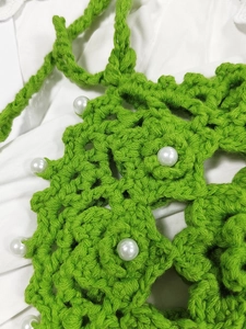 Close-up of green crochet crossbody bag with pearl beads and intricate knit texture