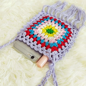 Detail of crochet crossbody bag showing capacity for phone and lipstick with fringe decor