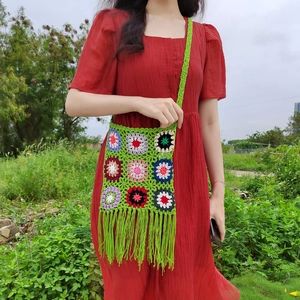 Close-up of handmade crochet granny square bag featuring vibrant floral patterns and long tassels