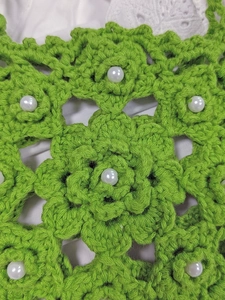 Close-up of green hand-crocheted floral crossbody bag with white pearl bead details