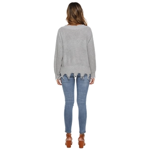 Detail view of grey knit sweater showing distressed ripped edges and fringe hem textures