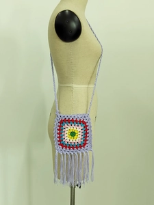 Detail of colorful granny square crochet crossbody bag with long purple fringe and strap