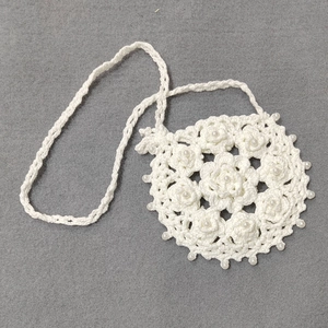 Detail of white crochet crossbody bag featuring 3D floral patterns and pearl beads