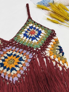 Close-up of bohemian multi-color granny square crochet pattern with burgundy fringe tassels