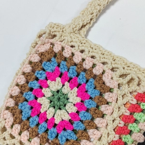 Close-up detail of hand-crocheted tote bag featuring colorful granny square floral pattern
