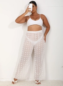 Detalle de pantalones de playa blancos de pierna ancha con malla transparente y lunares 3D