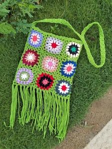 Detailed macro view of bohemian crochet flower patterns and long green fringe tassels