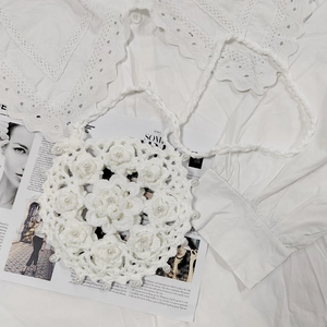 Detailed macro view of a white hand-crocheted round bag with 3D floral pearls