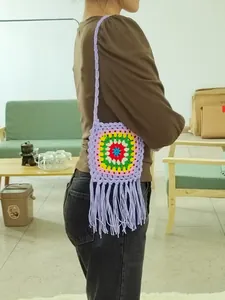 Detail of a handmade crochet crossbody bag featuring a granny square design and long fringes