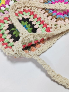 Close-up of vibrant crochet granny square stitching and reinforced handle on a handmade bag