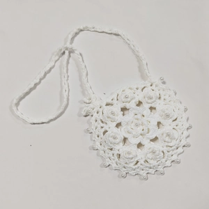Close-up of white crochet crossbody bag with floral knit texture and pearl details