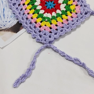 Detail of colorful hand-crocheted bag featuring floral knit patterns and purple strap